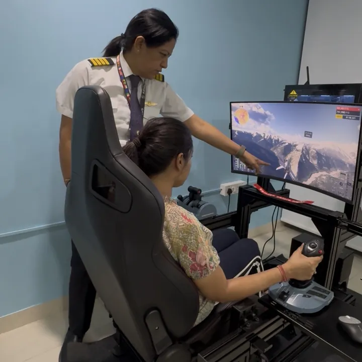 Pilot mentor in uniform guiding a student through a flight simulator session at Aerogenesis Bangalore